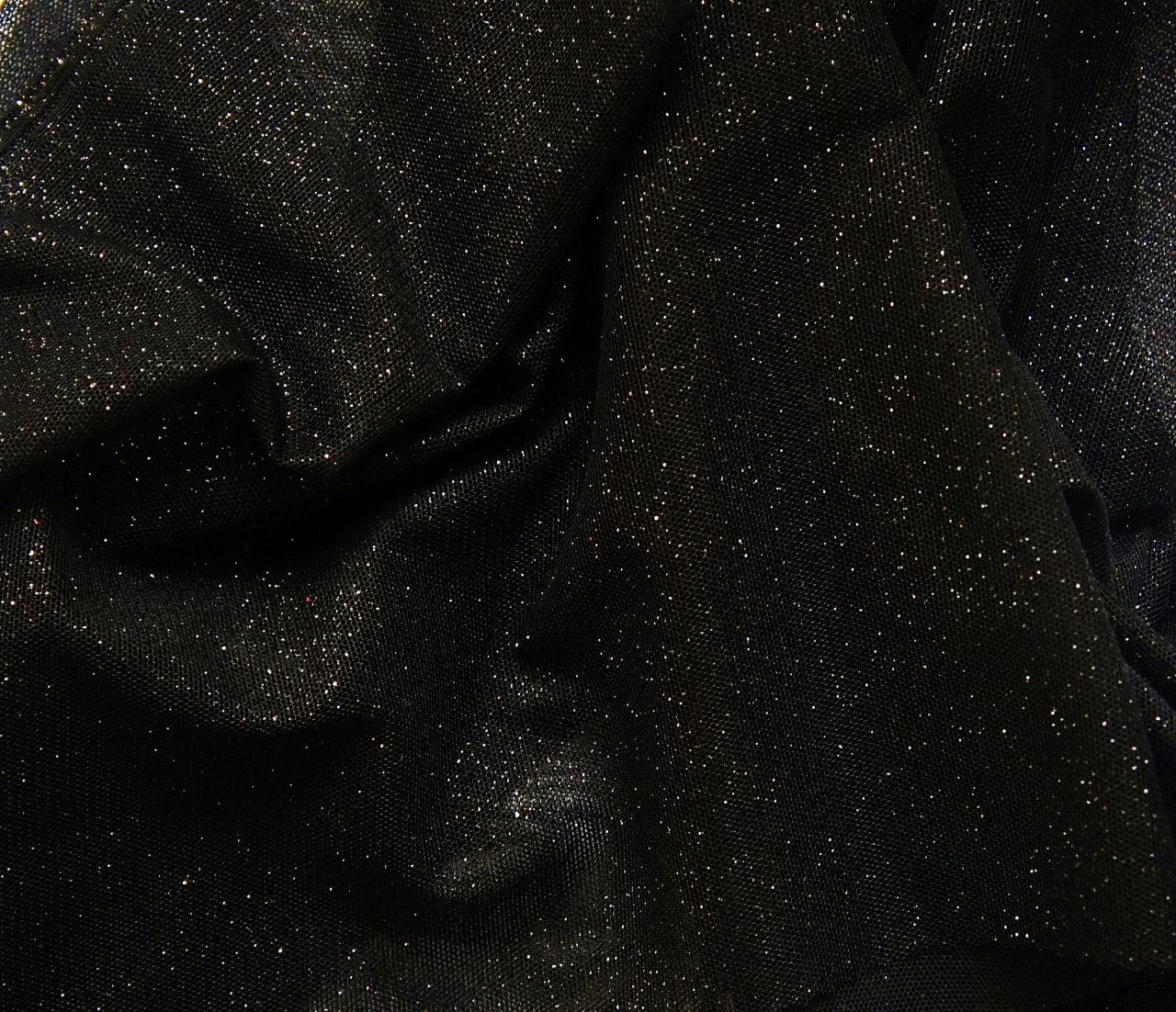 Black Glitter Mesh fabric features all over black glitter on 2-way stretch black polyester mesh making it ideal for both semi-fitted and draped garments.
